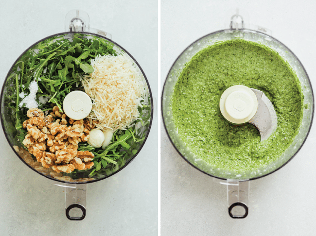 Arugula, walnuts, and parmesan cheese being blended into pesto by a food processor.