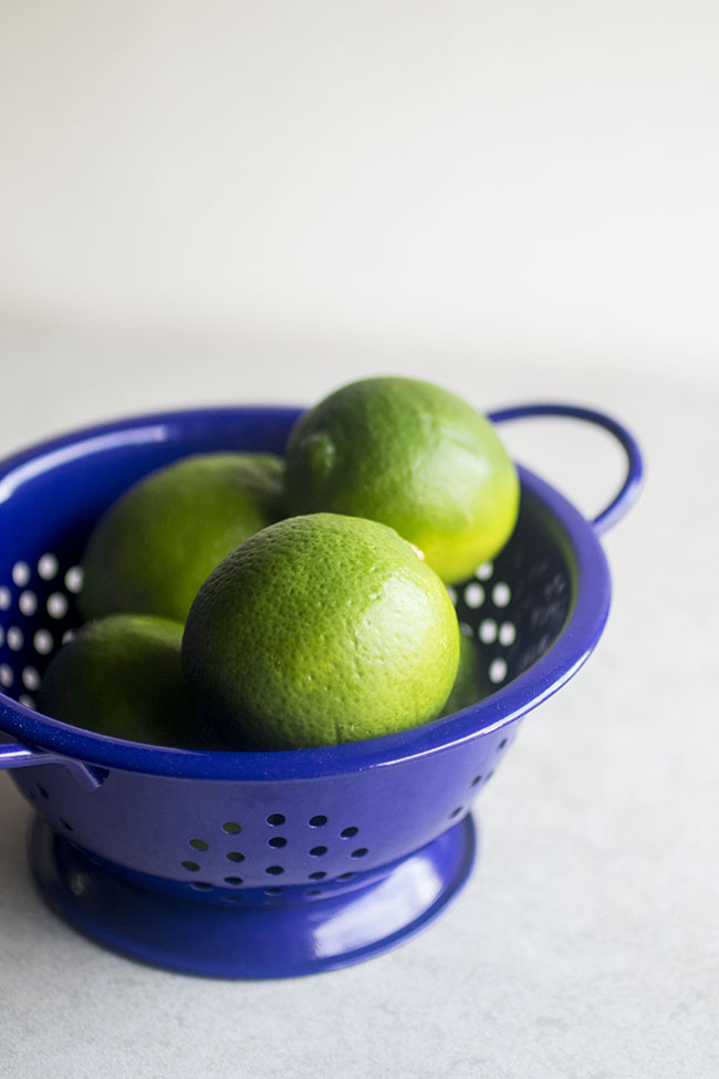 Limes in a bright blue colander.