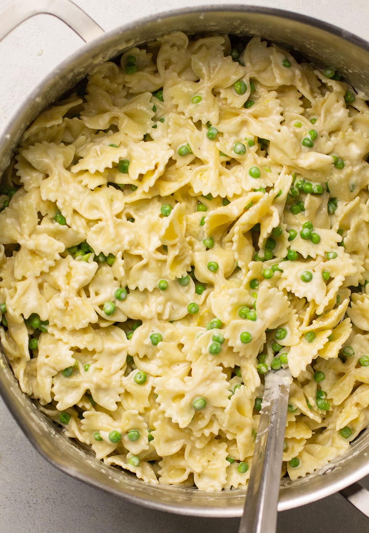 Creamy lemon pasta in a large saucepan with a silver spoon.